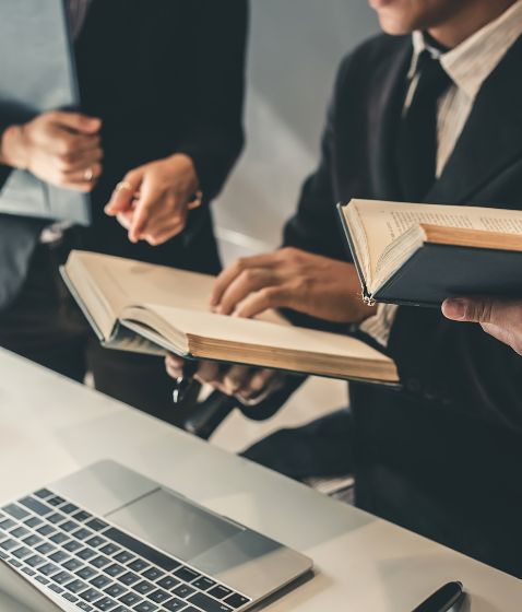 Personas revisando libros legales junto a una computadora portátil en una oficin